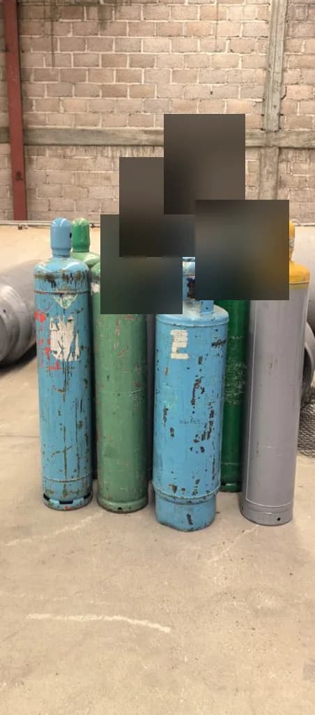 Cilindros de recuperación de refrigerante en acopio industrial con etiquetas censuradas, ECOSAVE del Norte