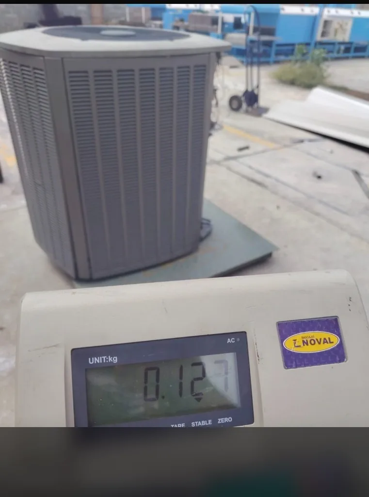 Báscula electrónica registrando peso de equipo de refrigeración con overlay de ubicación censurado
